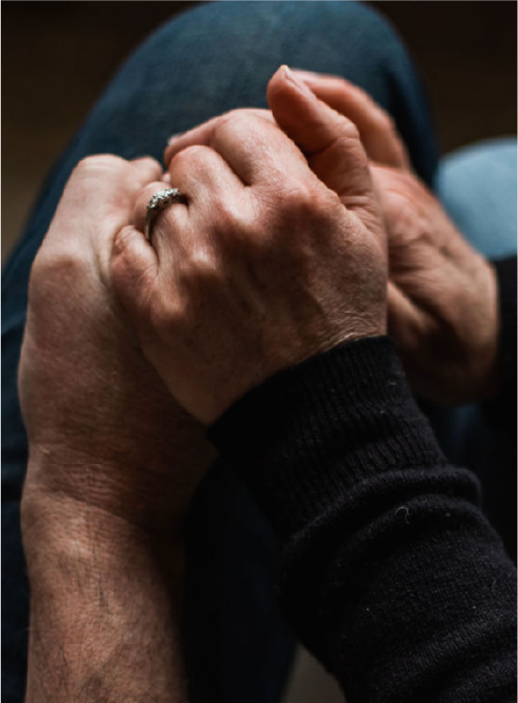 Close-up of elderly and younger hands holding each other, person wearing a ring on their ring finger.