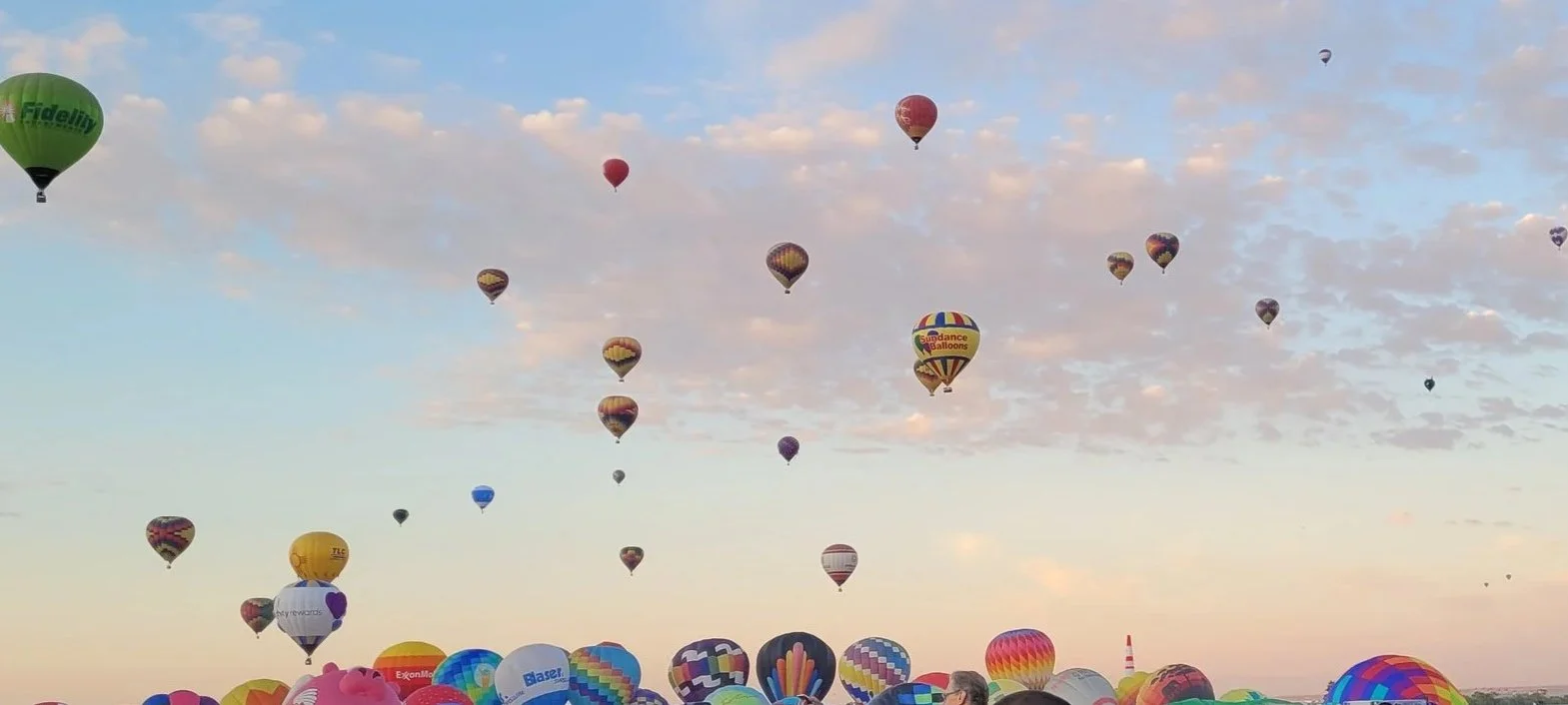 Hundreds of hot air balloons ascend into the sky at sunrise in Albuquerque, New Mexico at the annual Balloon Fiesta.