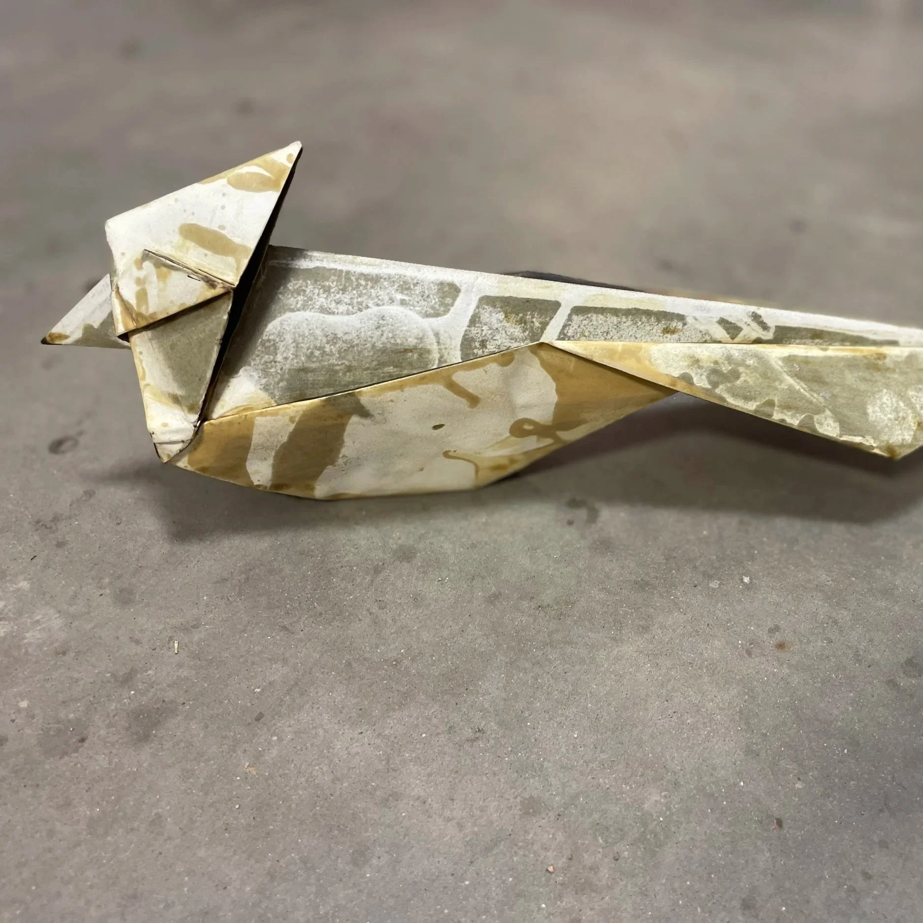 A paper airplane resting on a gray surface.
