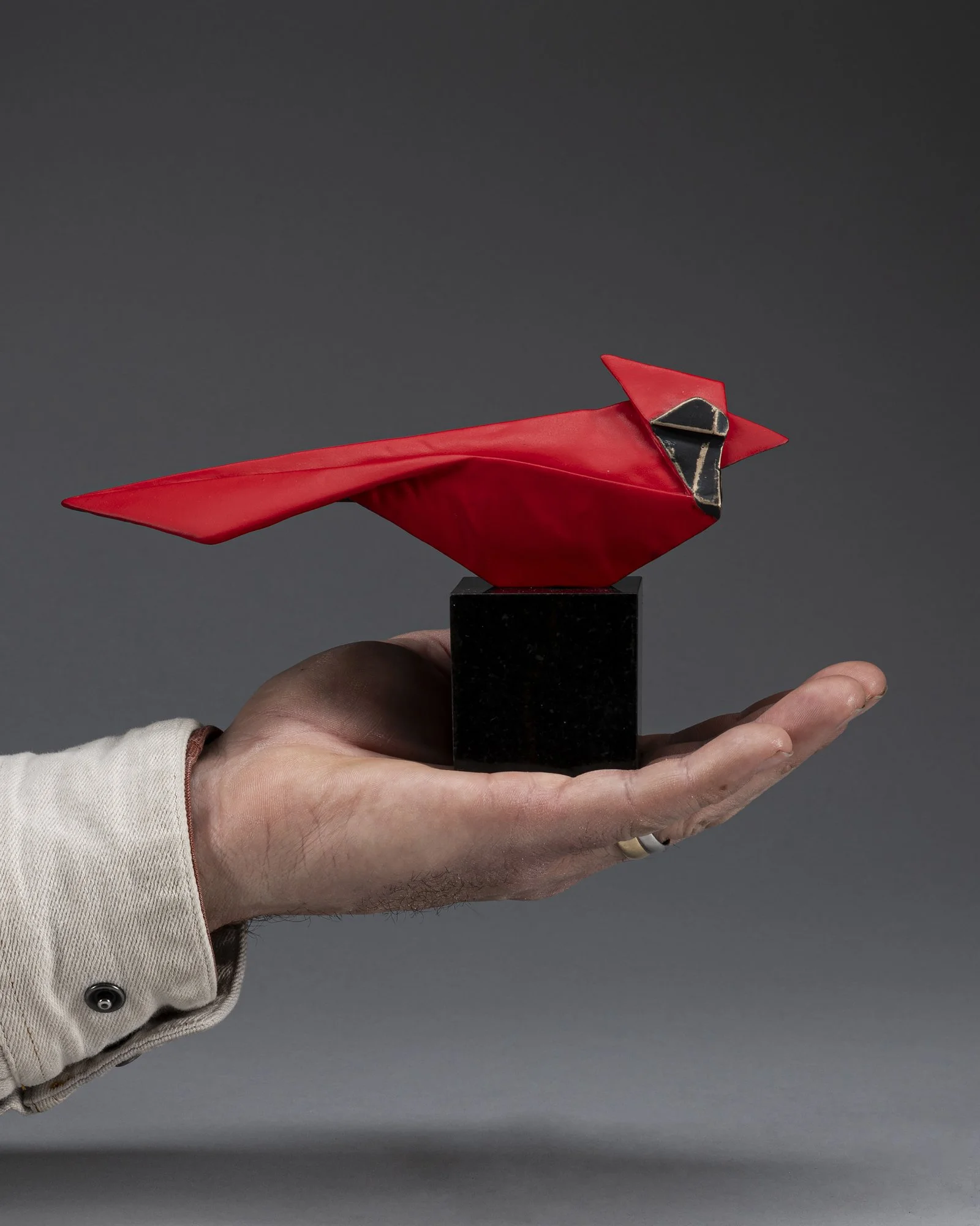 cast bronze sculpture of an origami cardinal mini size in the artist's hand