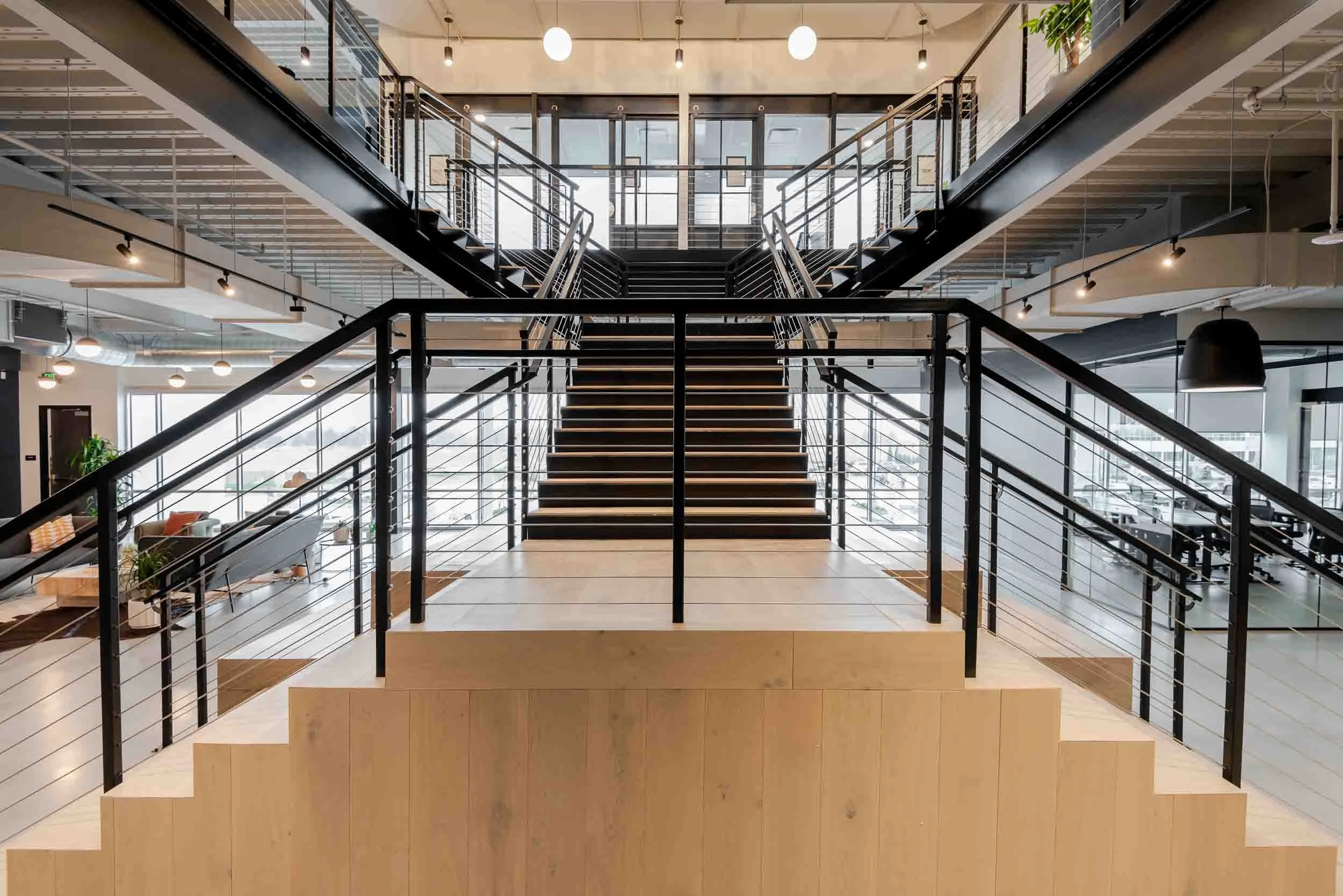 Interior of a modern, multi-floor office building with a central staircase, glass walls, and open workspace areas.