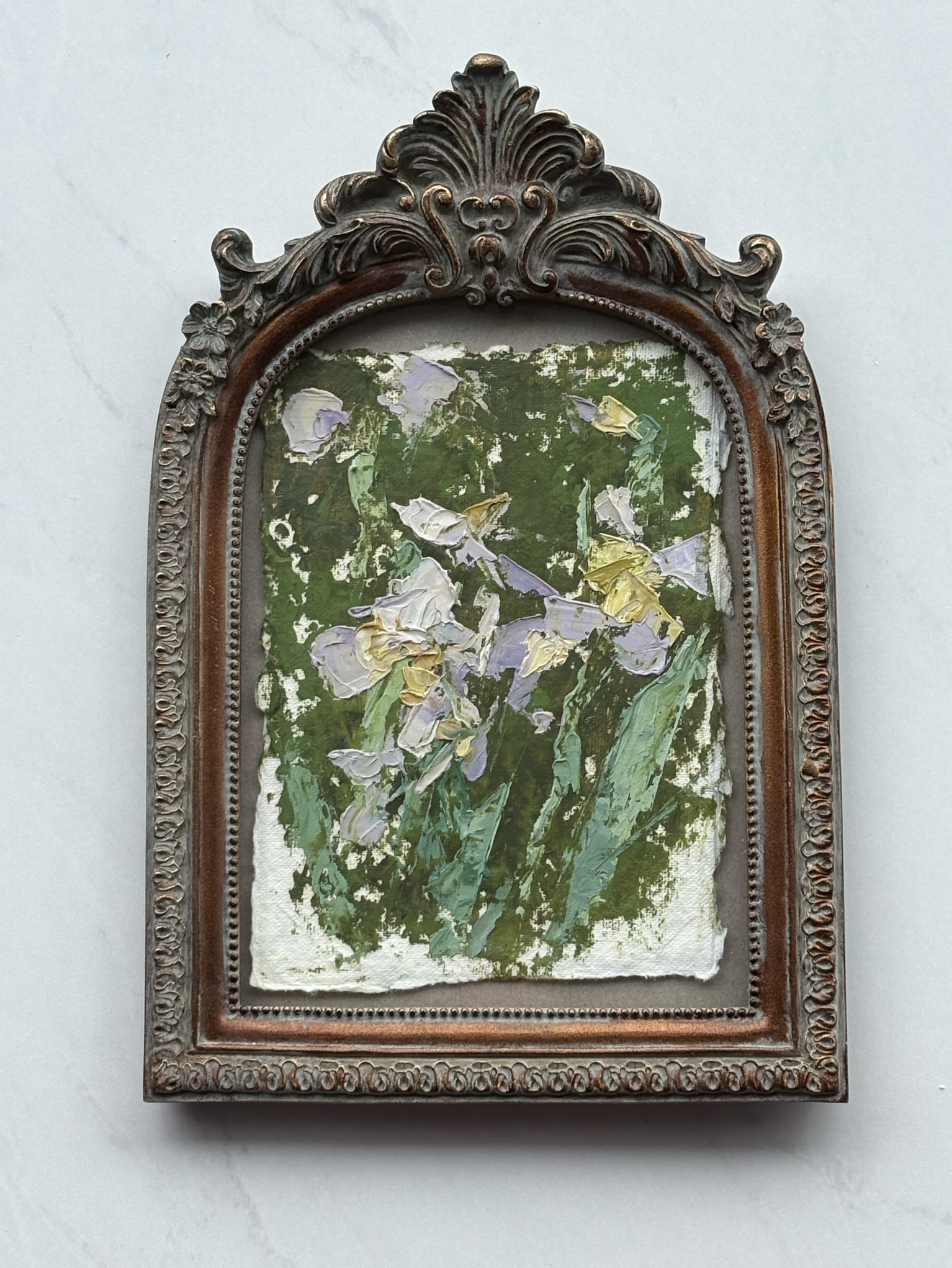 Painted artwork of irises with green leaves, framed in an ornate wooden and metal frame.