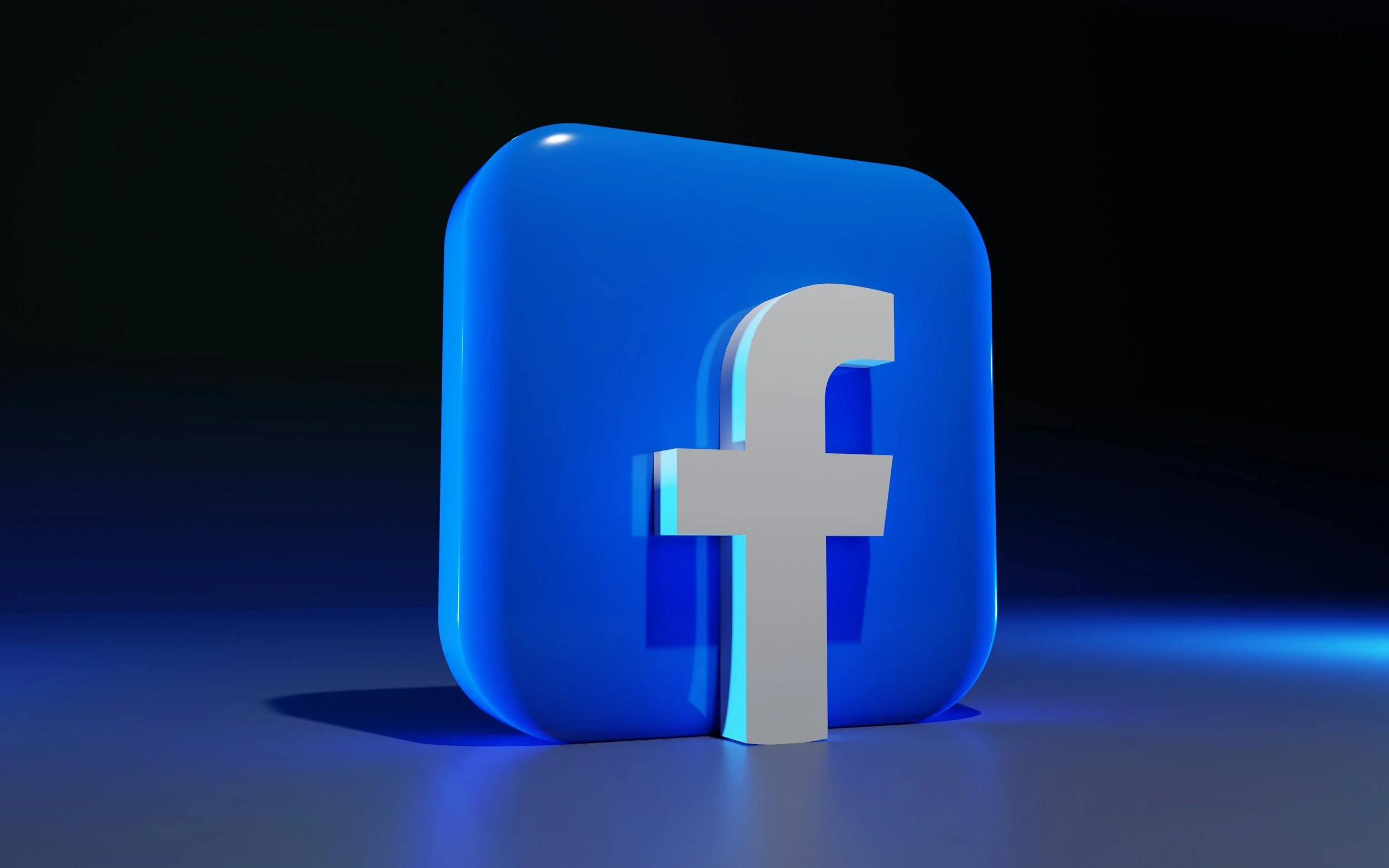 3D Facebook logo with a blue rounded square background and a white lowercase 'f' in the center, set against a dark background.