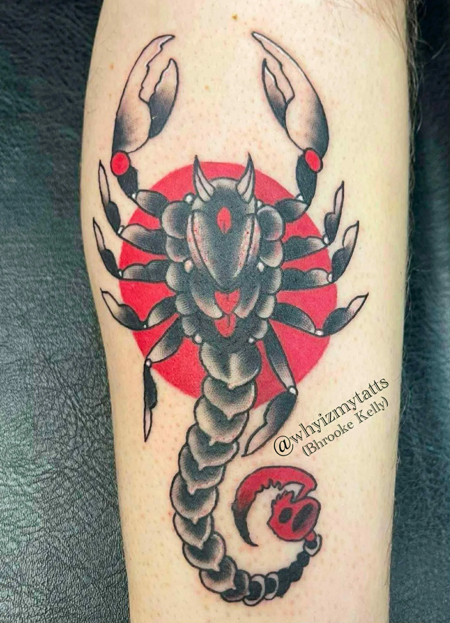 Tattoo of a black scorpion with red accents and a red background, along with a red and black snake design, on a person's arm.