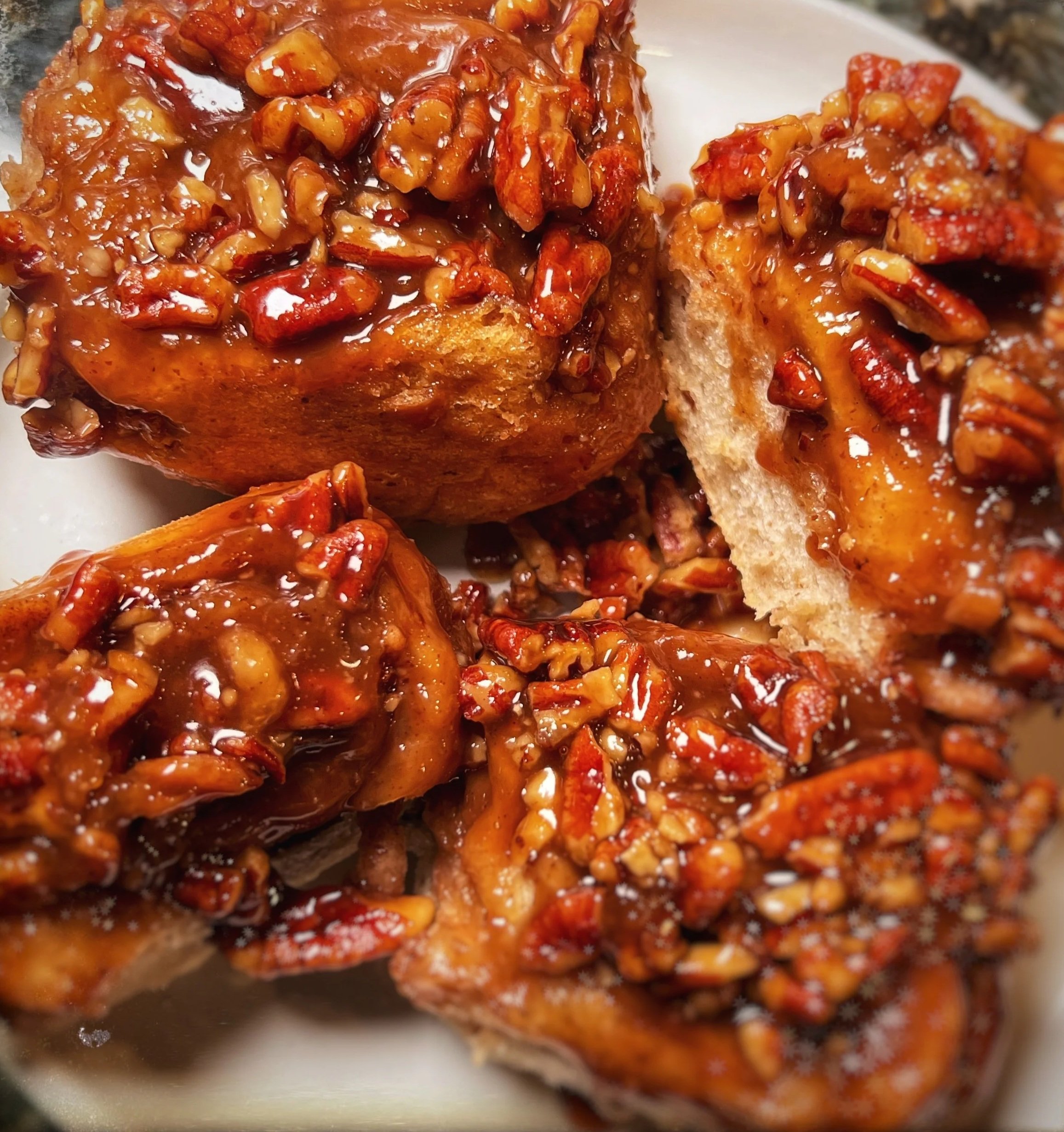 Close-up of pecan sticky buns topped with caramel sauce and chopped pecans.