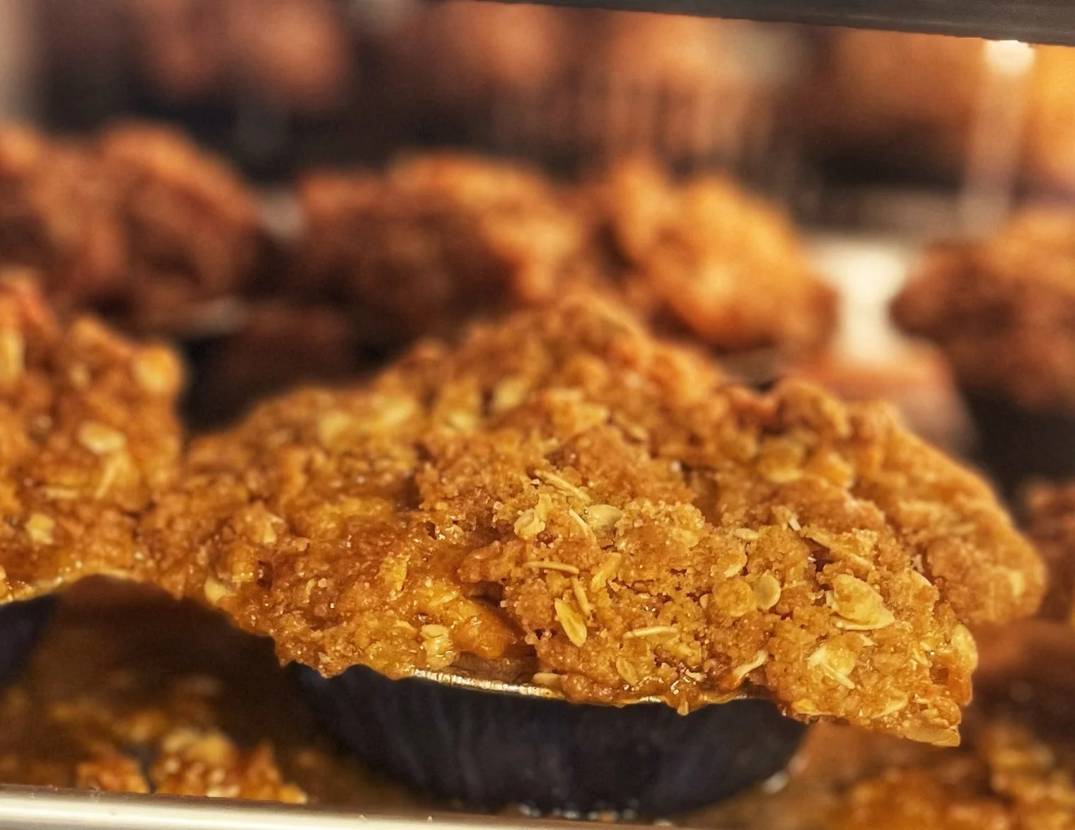 Close-up of an oatmeal cookie on a baking sheet with other cookies in the background.