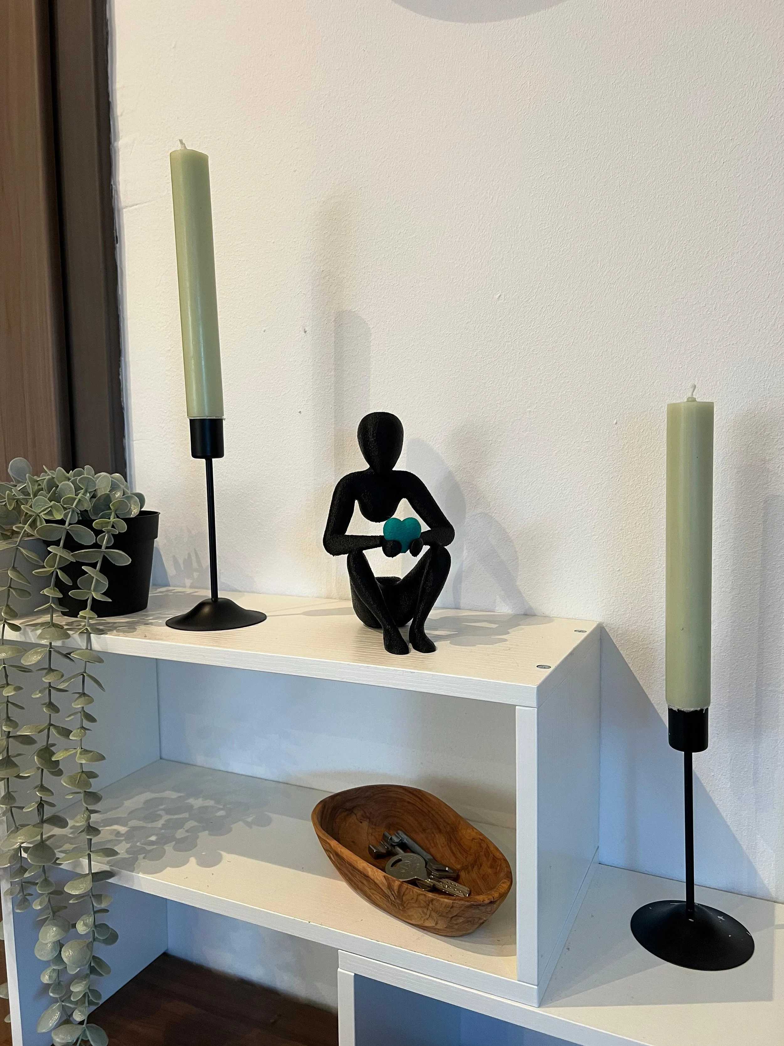 Deko auf einer weißen Ablage mit Kerzen, Figur und Schüssel