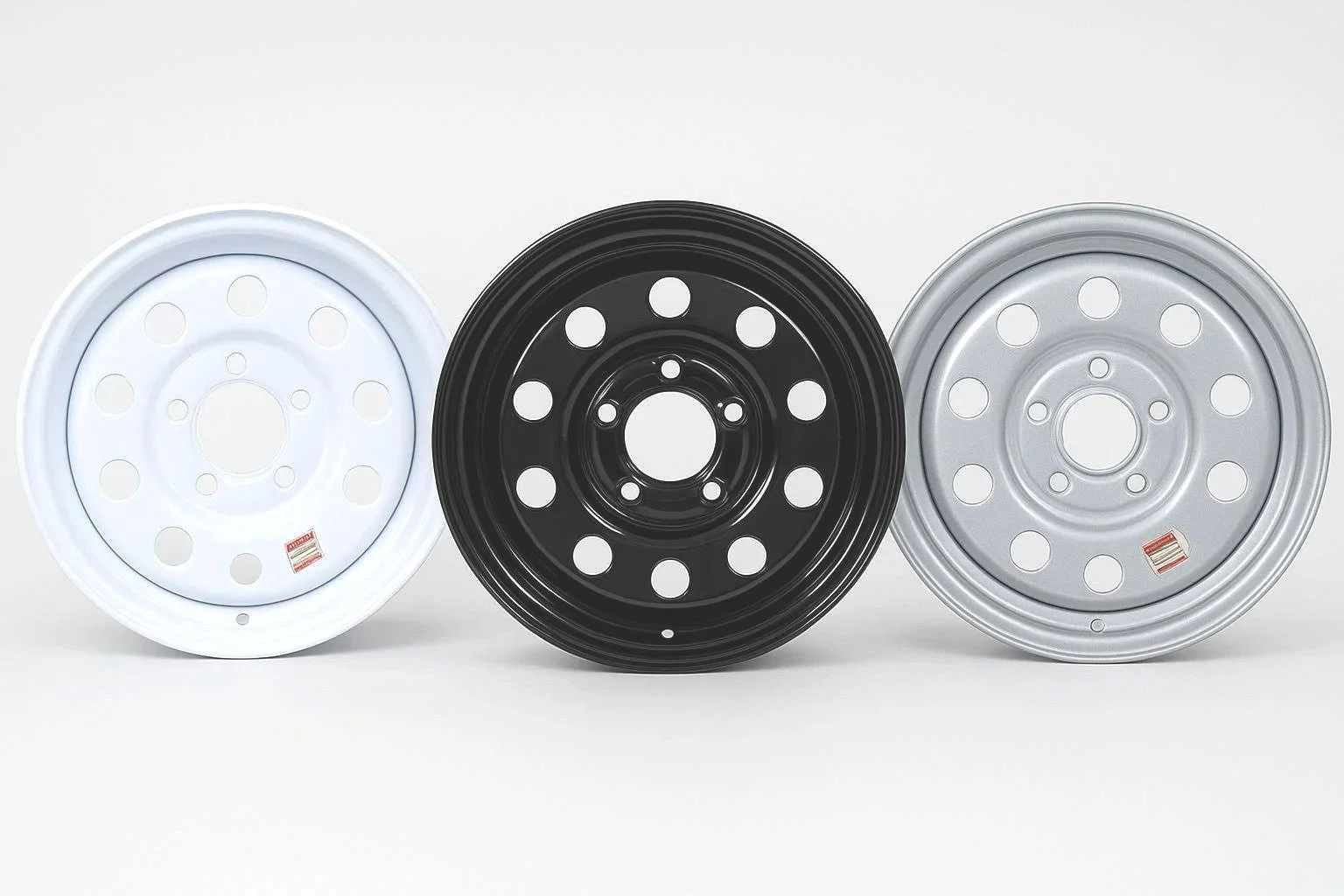 Three steel wheel rims in white, black, and silver, arranged side by side on a white background.