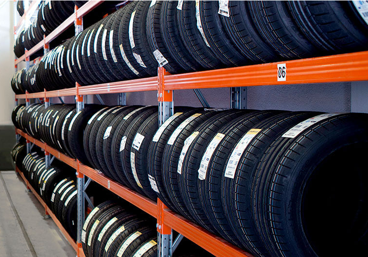 Multiple shelves filled with car tires in a tire warehouse.