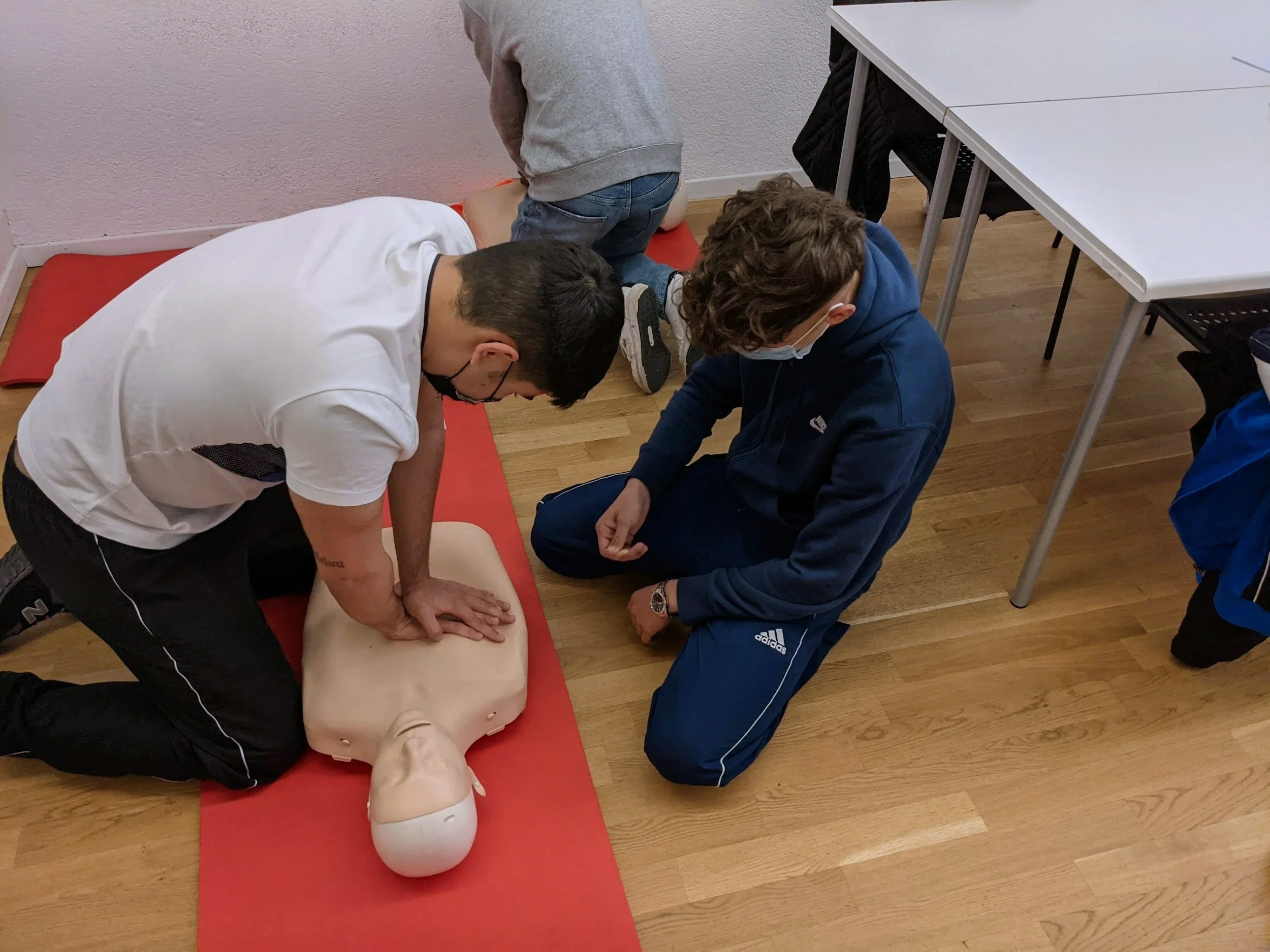 Instructor demonstrating CPR technique on a training manikin during a first aid course