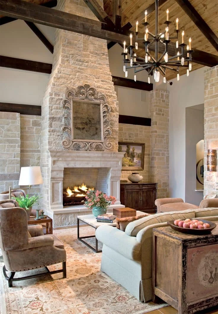 Living room with stone fireplace, chandelier, beige and brown furniture, and decorative accents.