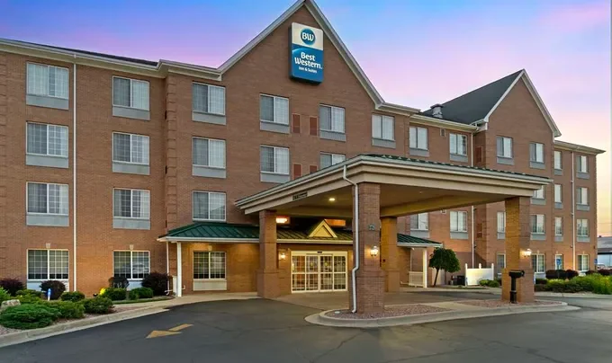 Exterior view of a Buger Western hotel with a brick facade, green accents, and a covered entrance, during sunset