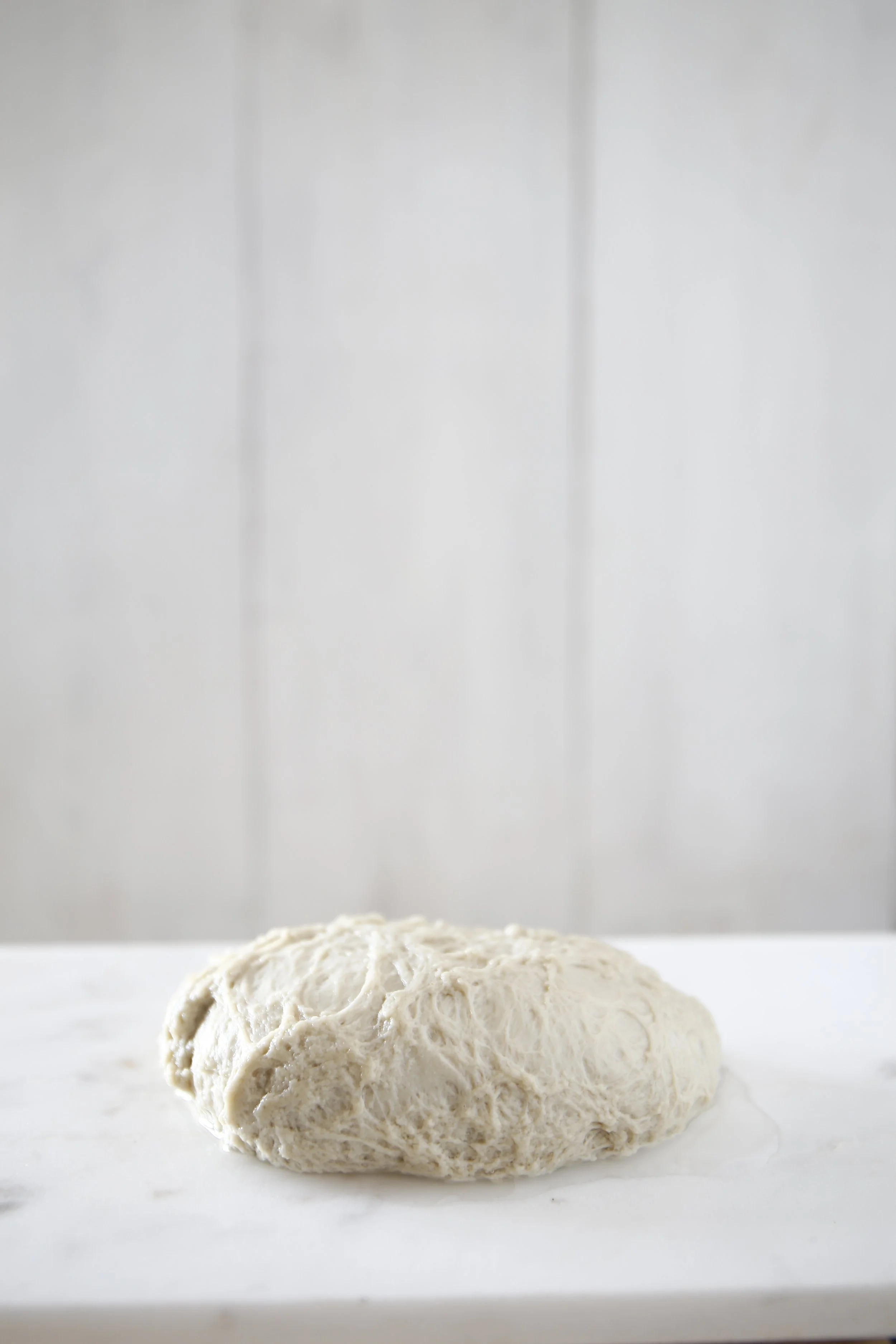 Massa de pão branca e moles sobre uma superfície branca, fundo de parede clara.