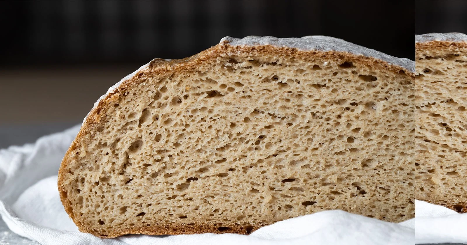 Fatia de pão integral descansando sobre uma toalha branca.