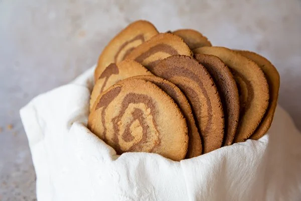 Biscoitos de manteiga com padrão de espiral, em uma tigela branca.