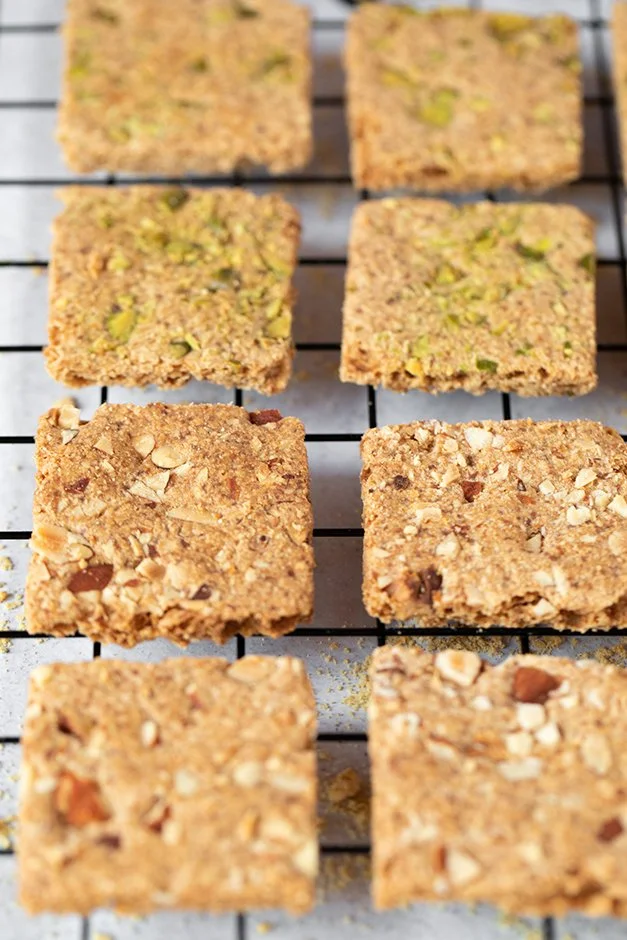 Cubos de barra de cereal ou biscoitos caseiros enfileirados em uma grade de resfriamento.