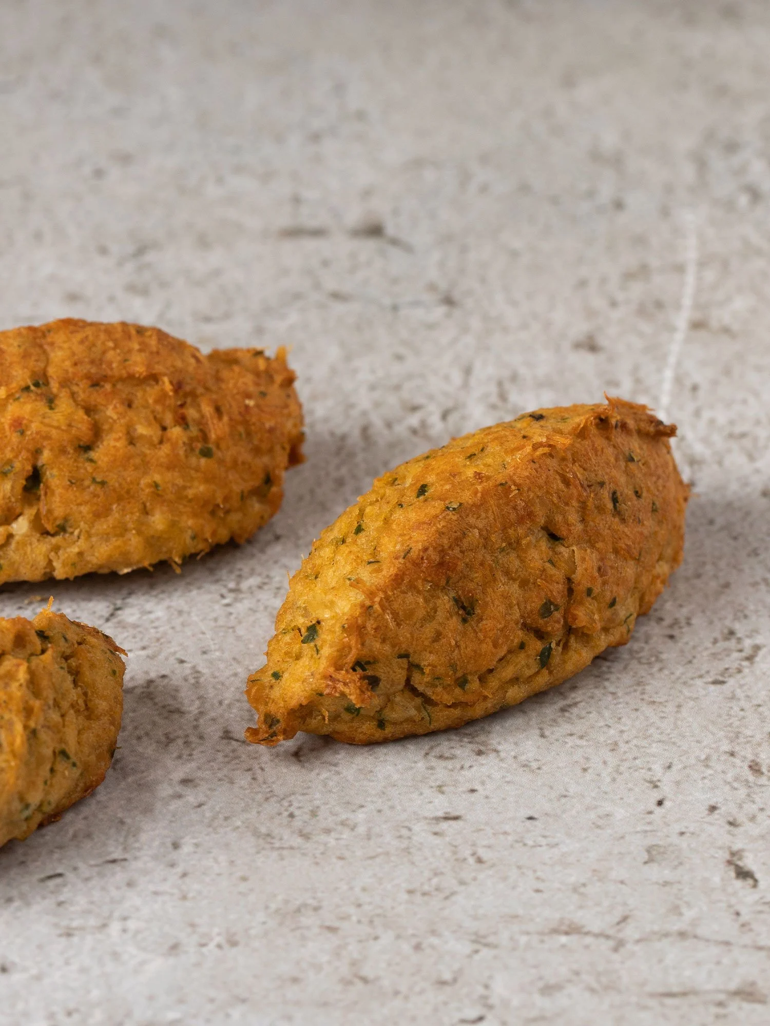 Três croquetes de carne assados sobre uma superfície clara