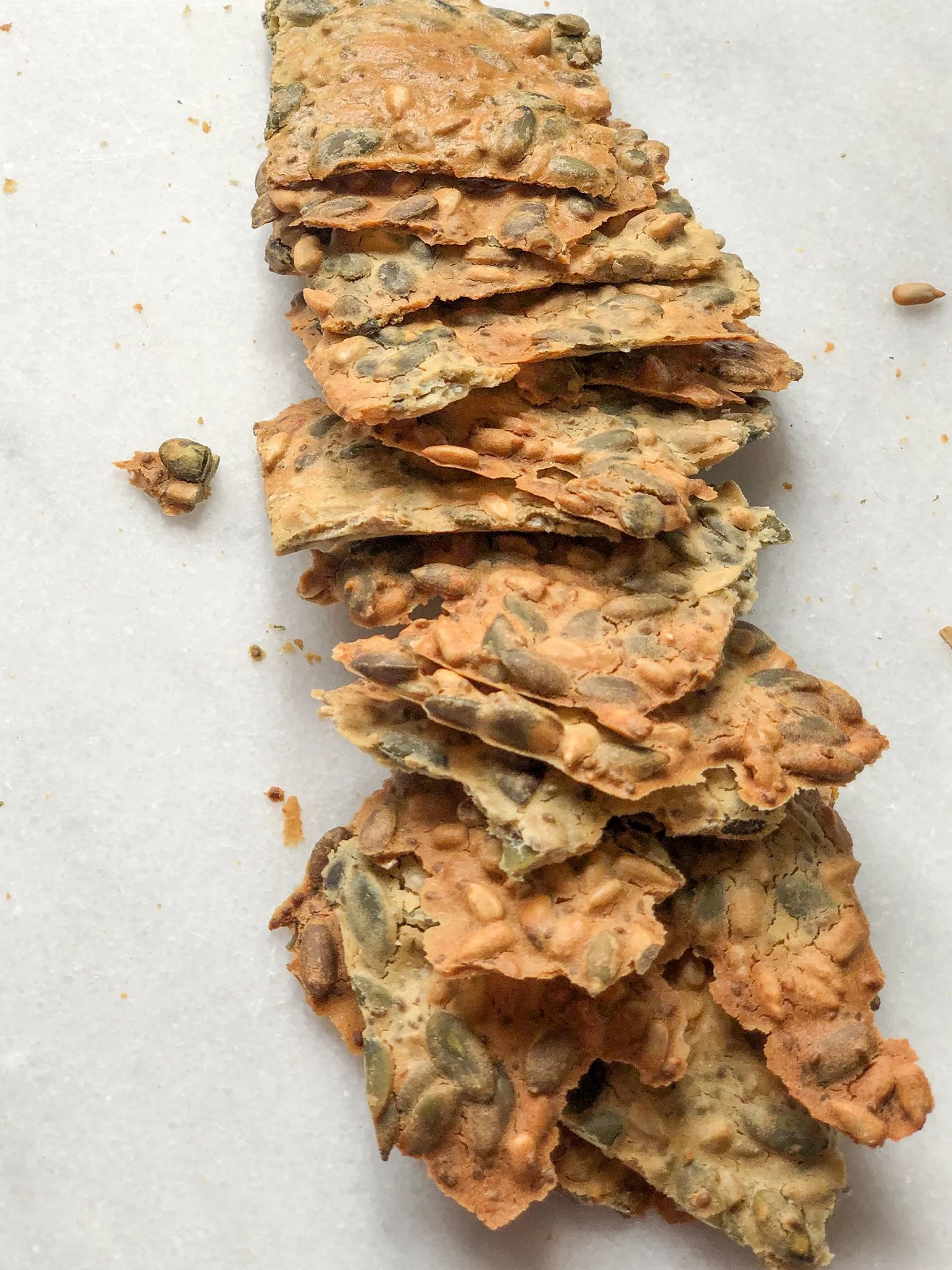 Fatias de biscoito de sementes de abóbora e linhaça sobre fundo branco.