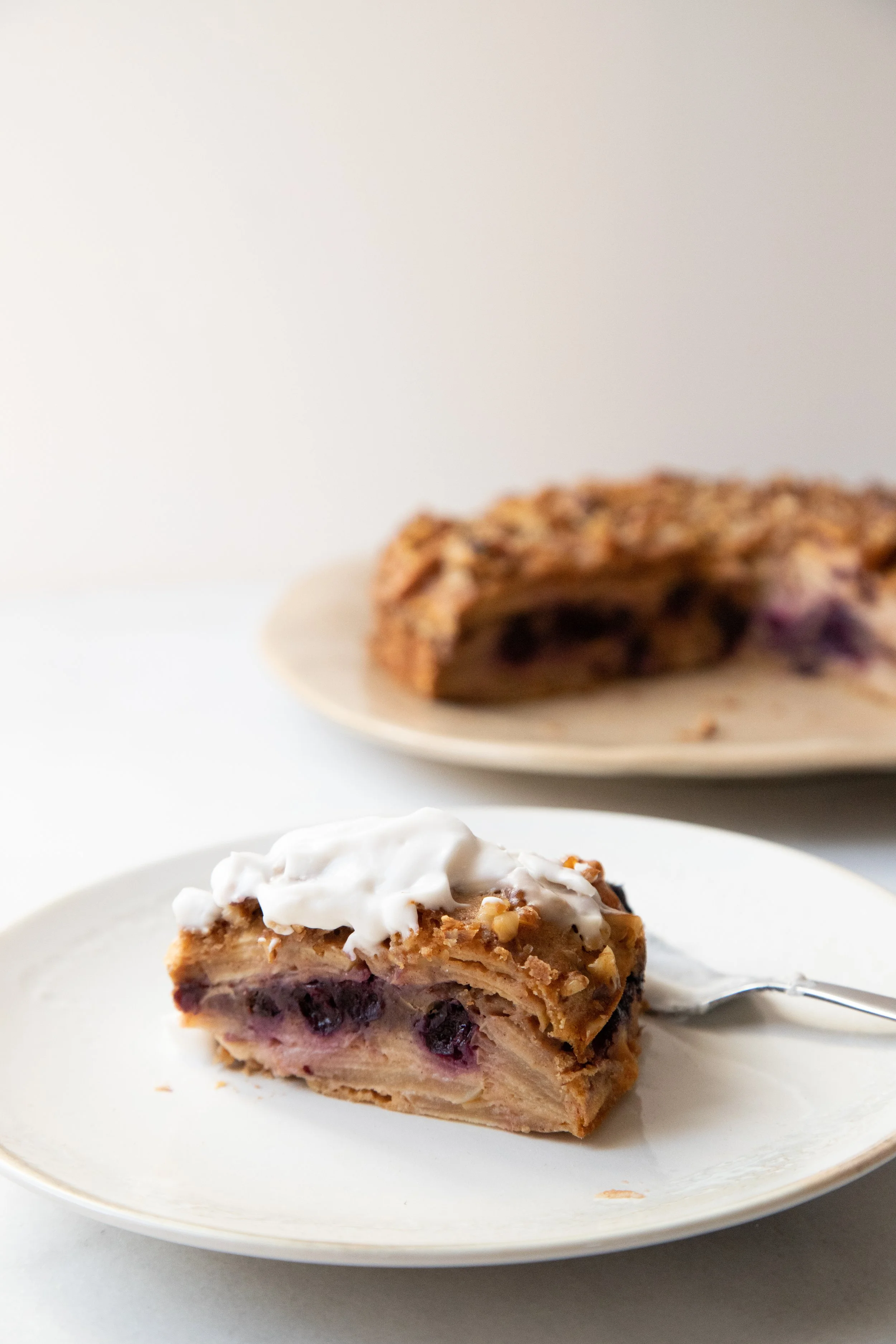 Fatia de torta de maçã com blueberries e cobertura de chantilly em um prato branco
