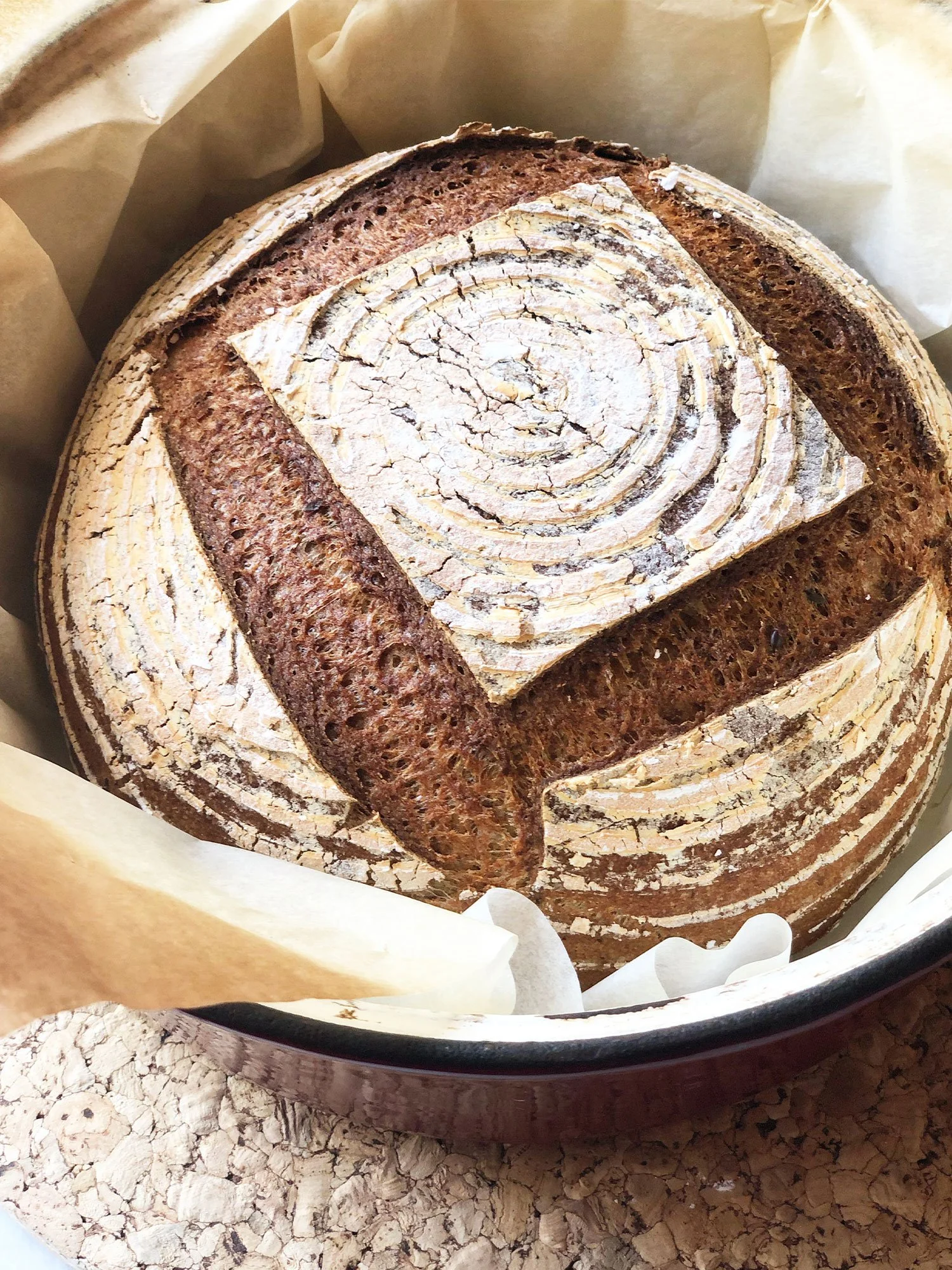Pão artesanal de fermentação natural com padrão de crosta rústica e m quanto de tiras circulares na superfície.