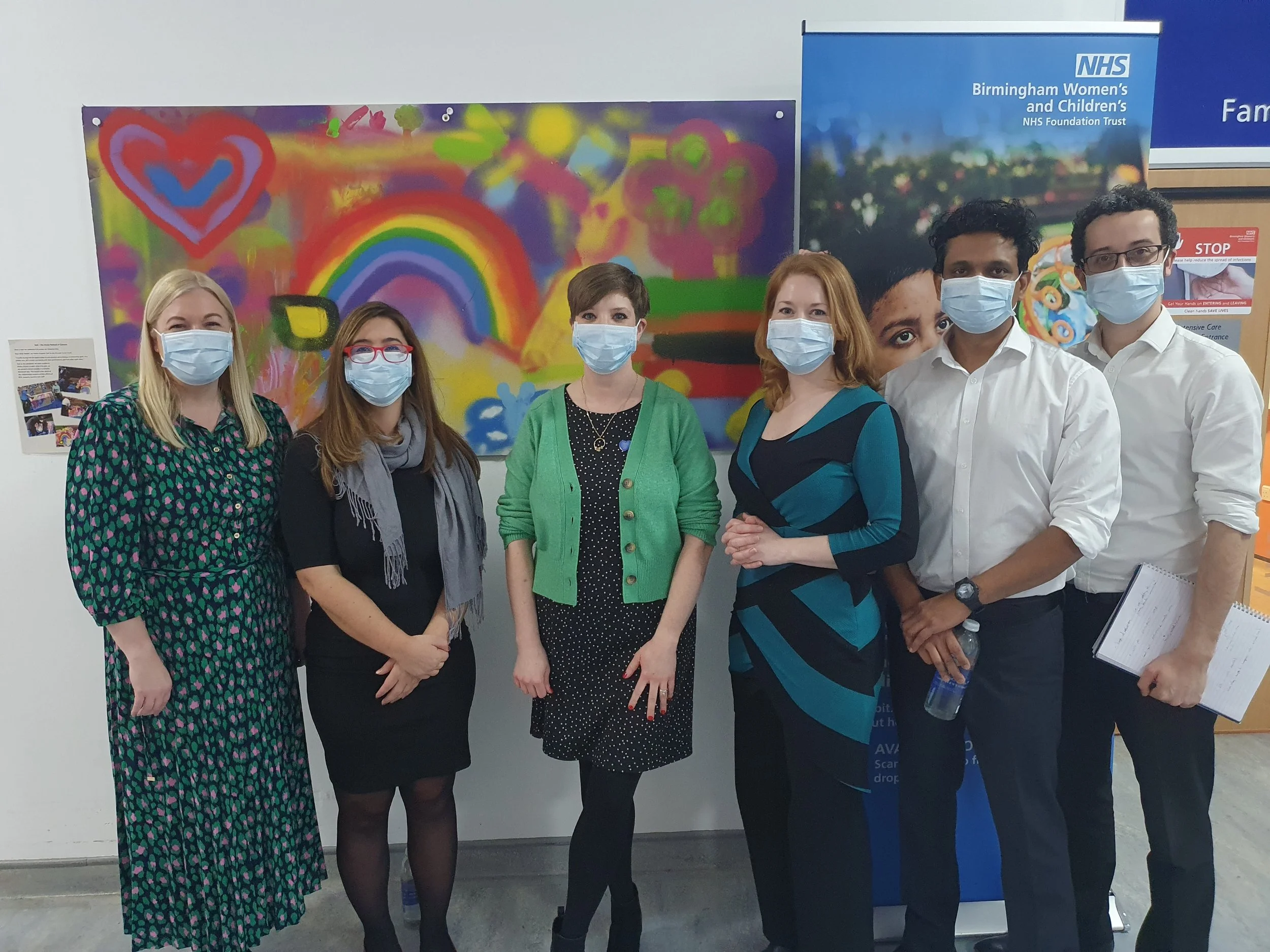 A group of contract consultants stand together in a Birmingham hospital wearing medical masks. There are four, including the coach, Diana Squires, and with them is an NHS fundraising professional.