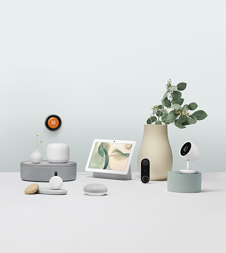 Collection of smart home devices, decor, and a plant on a white surface with a light blue background.