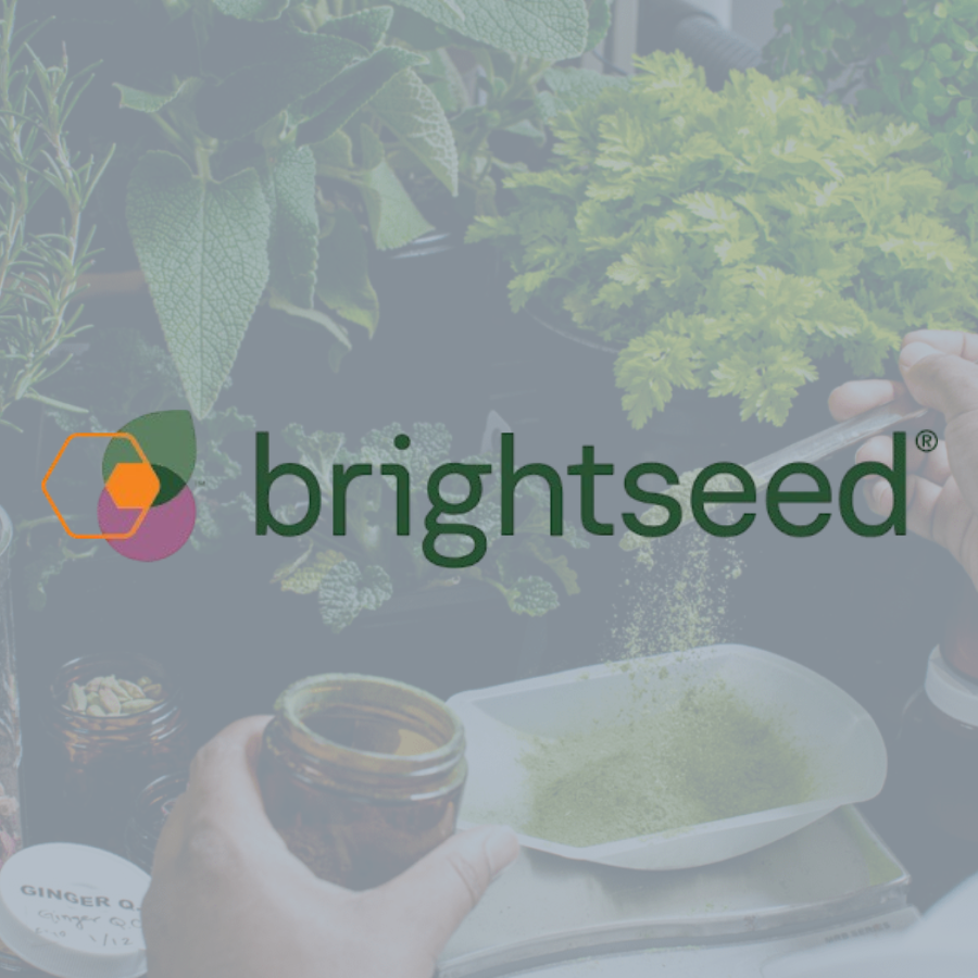 A person handling fresh herbs and spices, including parsley and ginger, on a table with a jar and a small dish of green powder, with the Brightseed logo overlaying the image.