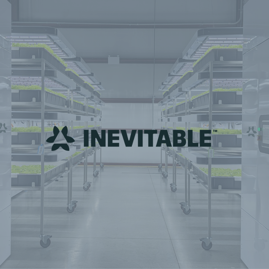 Interior of a modern indoor space with metal shelving units on wheels, holding trays of green plants, and a logo with the word 'INEVITABLE' overlayed.