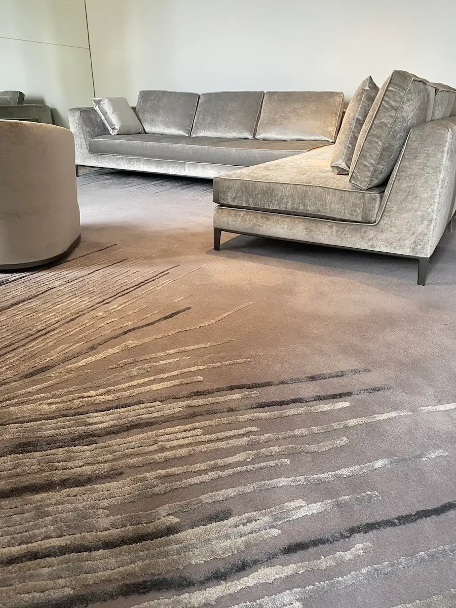 ChatGPT a dit :Modern living rooms featuring grey velvet sofas and a beige rug with black line patterns, set in an elegant and minimalist space.