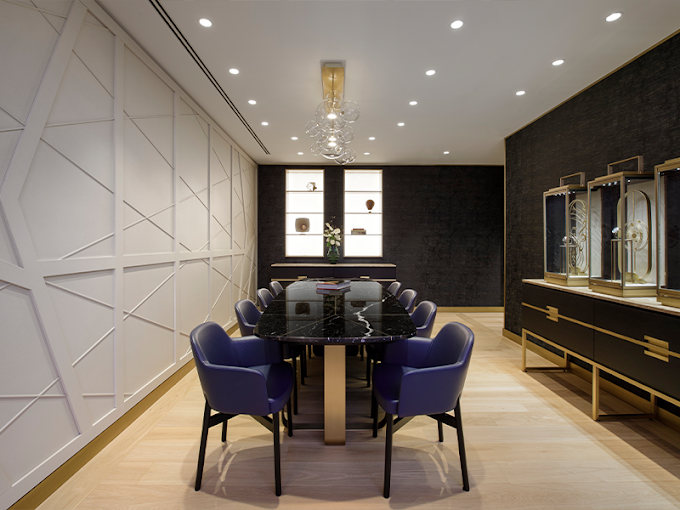 An elegant meeting room featuring a large black marble table, eight blue leather chairs, modern decorative walls, and display cabinets with gold decorative objects.