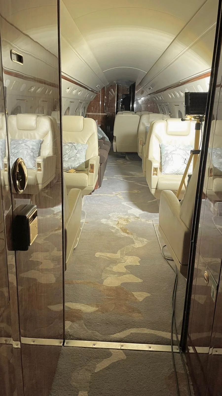 Intérieur d'un jet privé avec des sièges en cuir beige, un tapis beige à motifs et une cabine élégante vue de l'entrée.