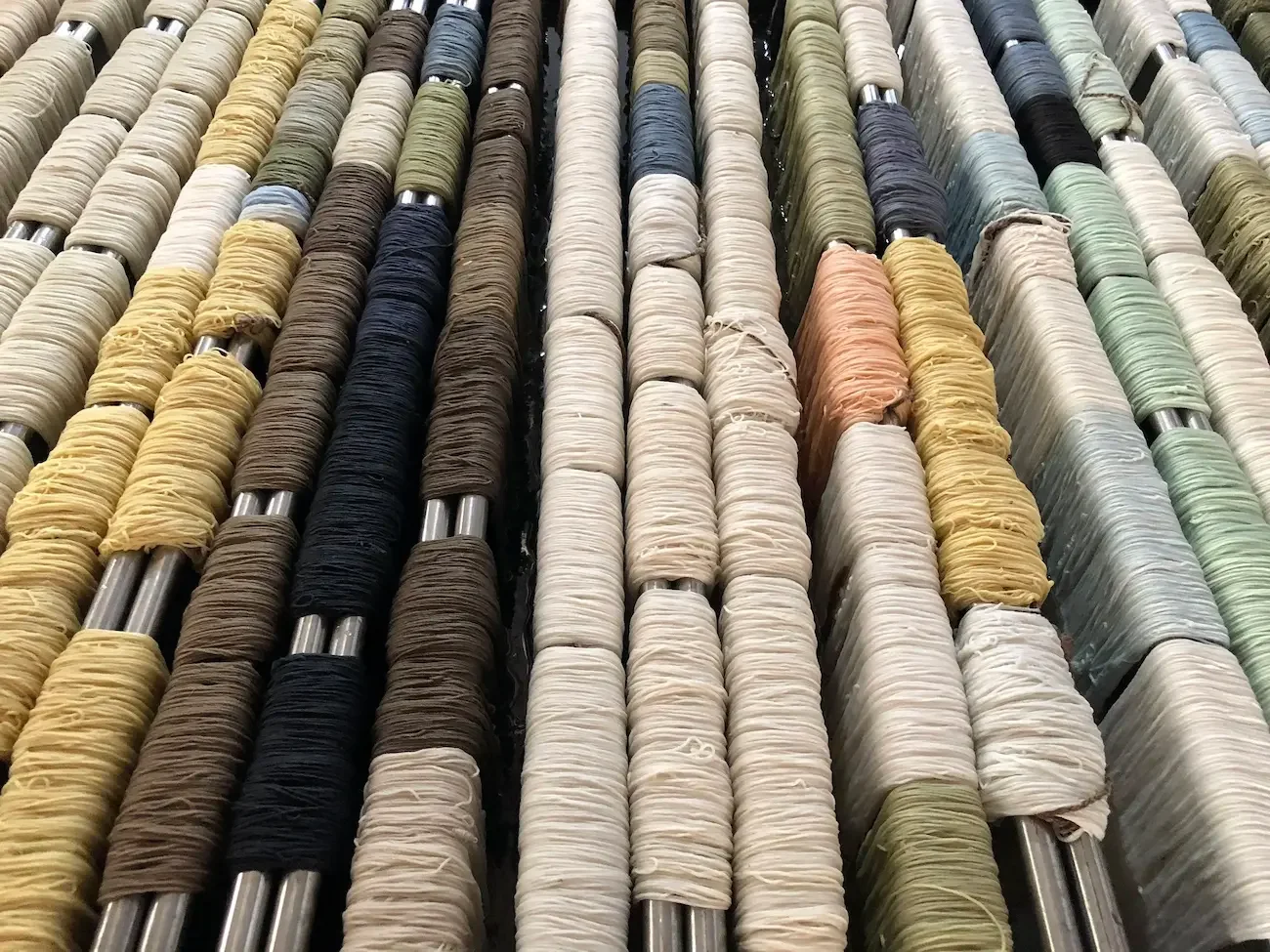 A rug featuring spools of thread in various colors arranged vertically.