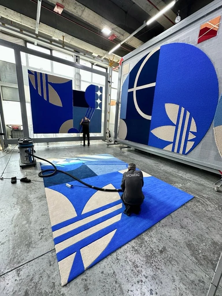 Artistes créant une œuvre abstraite en bleu, blanc et beige dans un atelier spacieux.