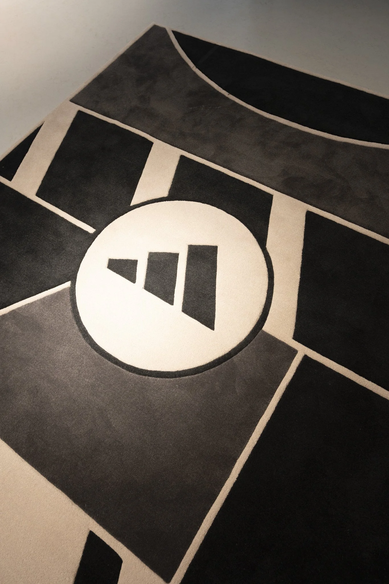 Une nappe ou un tapis avec un motif noir, blanc et gris, y compris un cercle avec un symbole ressemblant à un bouton de contrôle de volume.