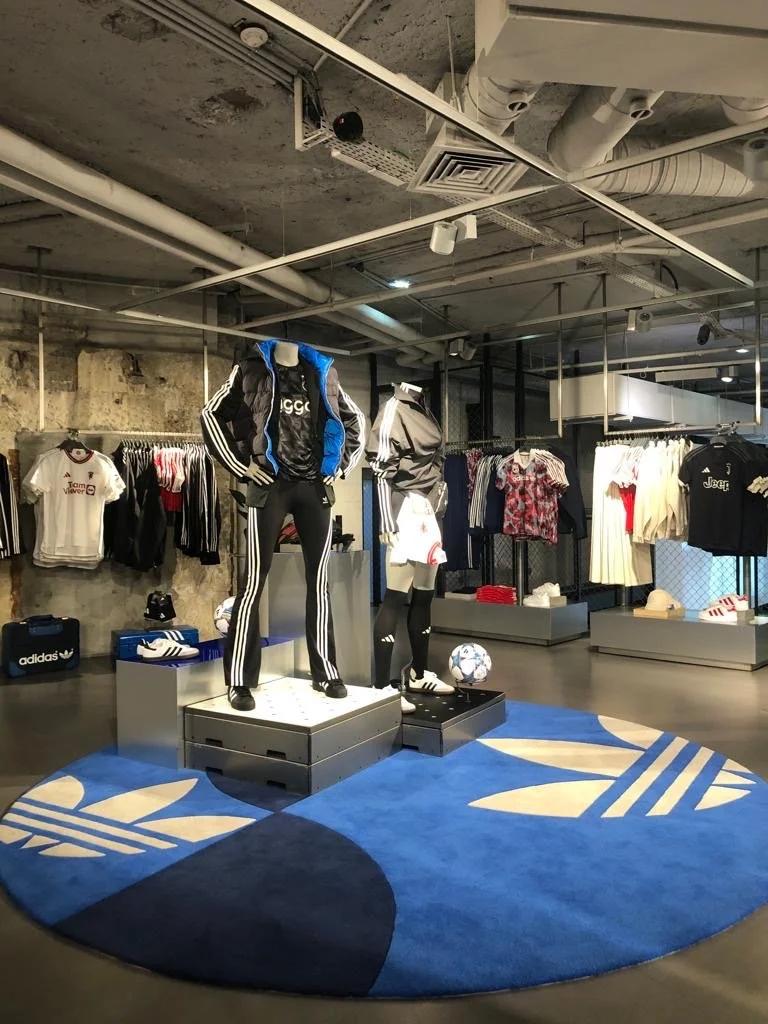 Vêtements de sport et accessoires de mode, y compris des mannequins habillés d'ensembles Adidas, dans un magasin de vêtements de sport.