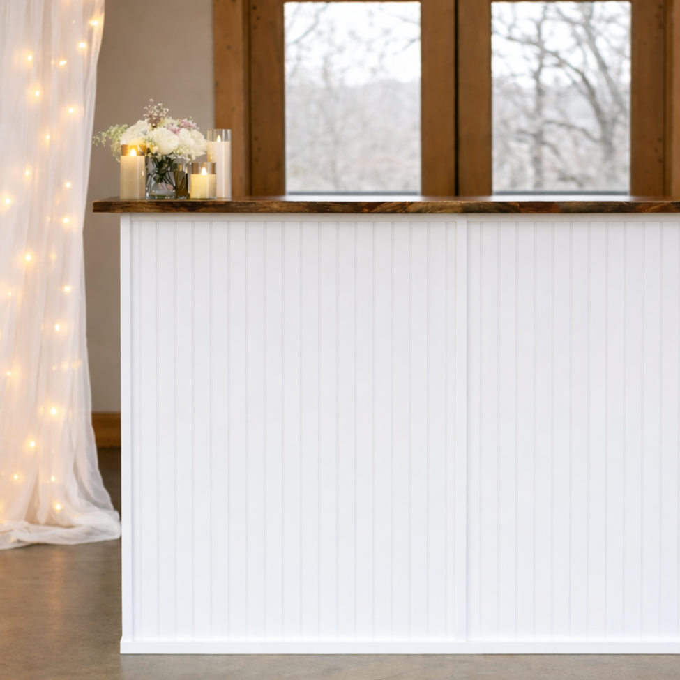 A decorated coffee bar with flowers and candles, set in a room with wooden accents and large windows.