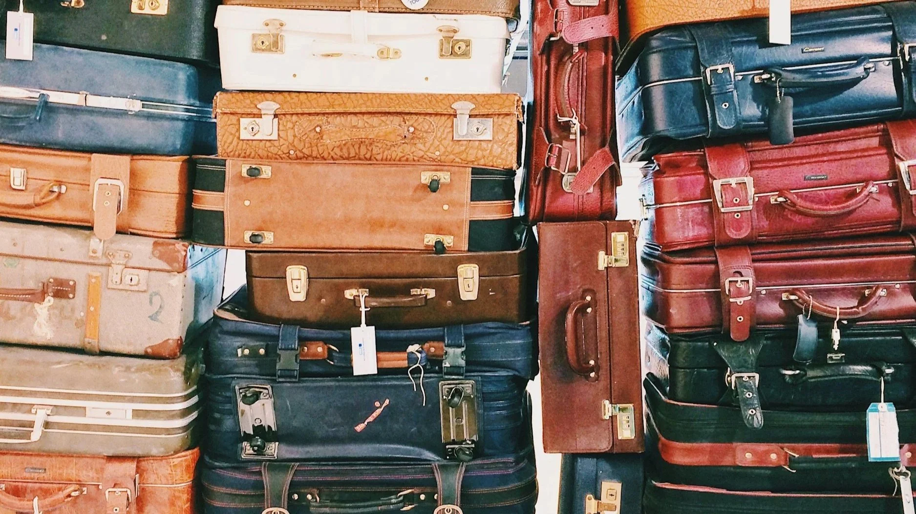 Stacked vintage suitcases in various colors and sizes.