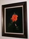 Framed painting of an orange flower with green leaves on a black background.