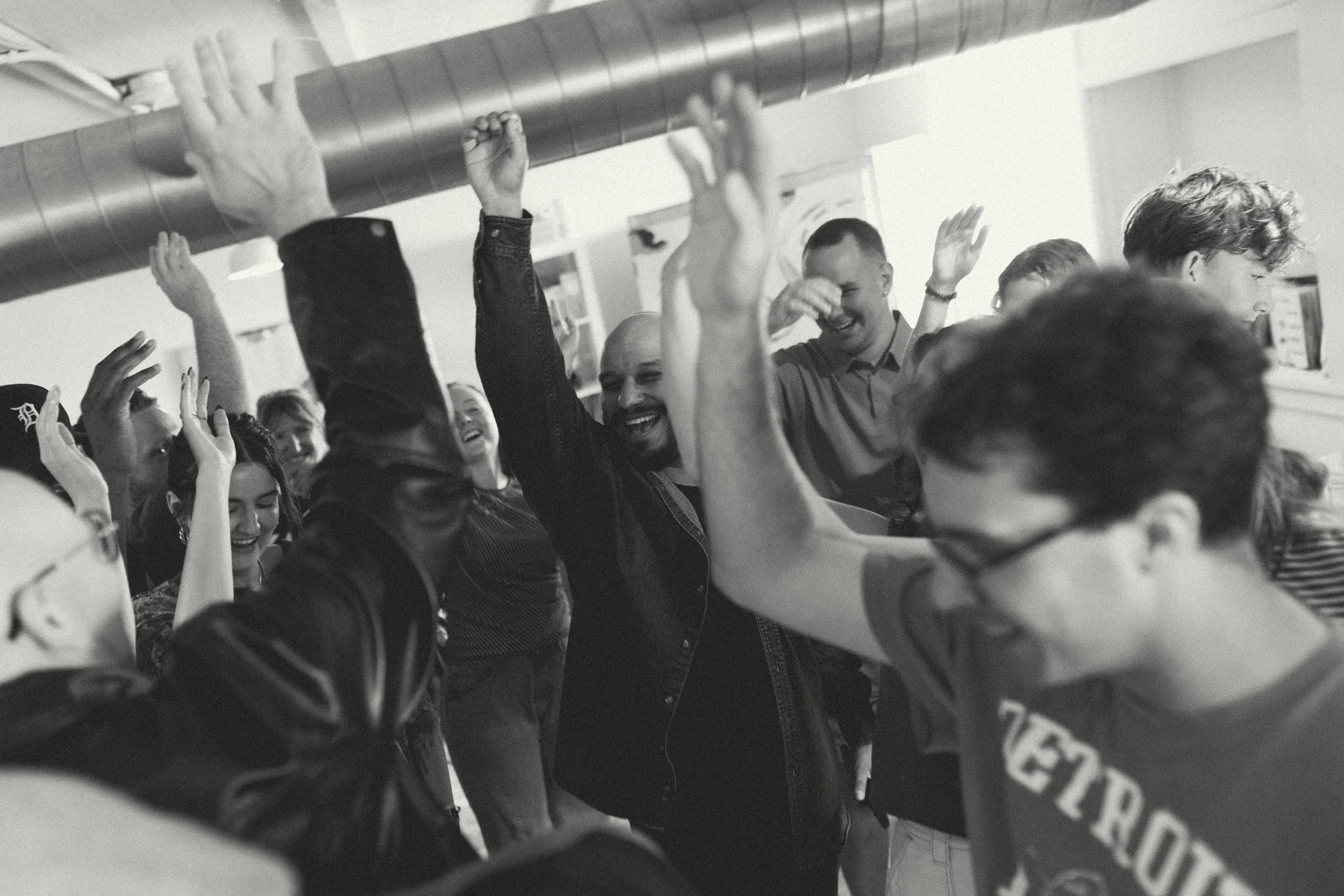Group of people celebrating and high-fiving indoors, black-and-white photo.