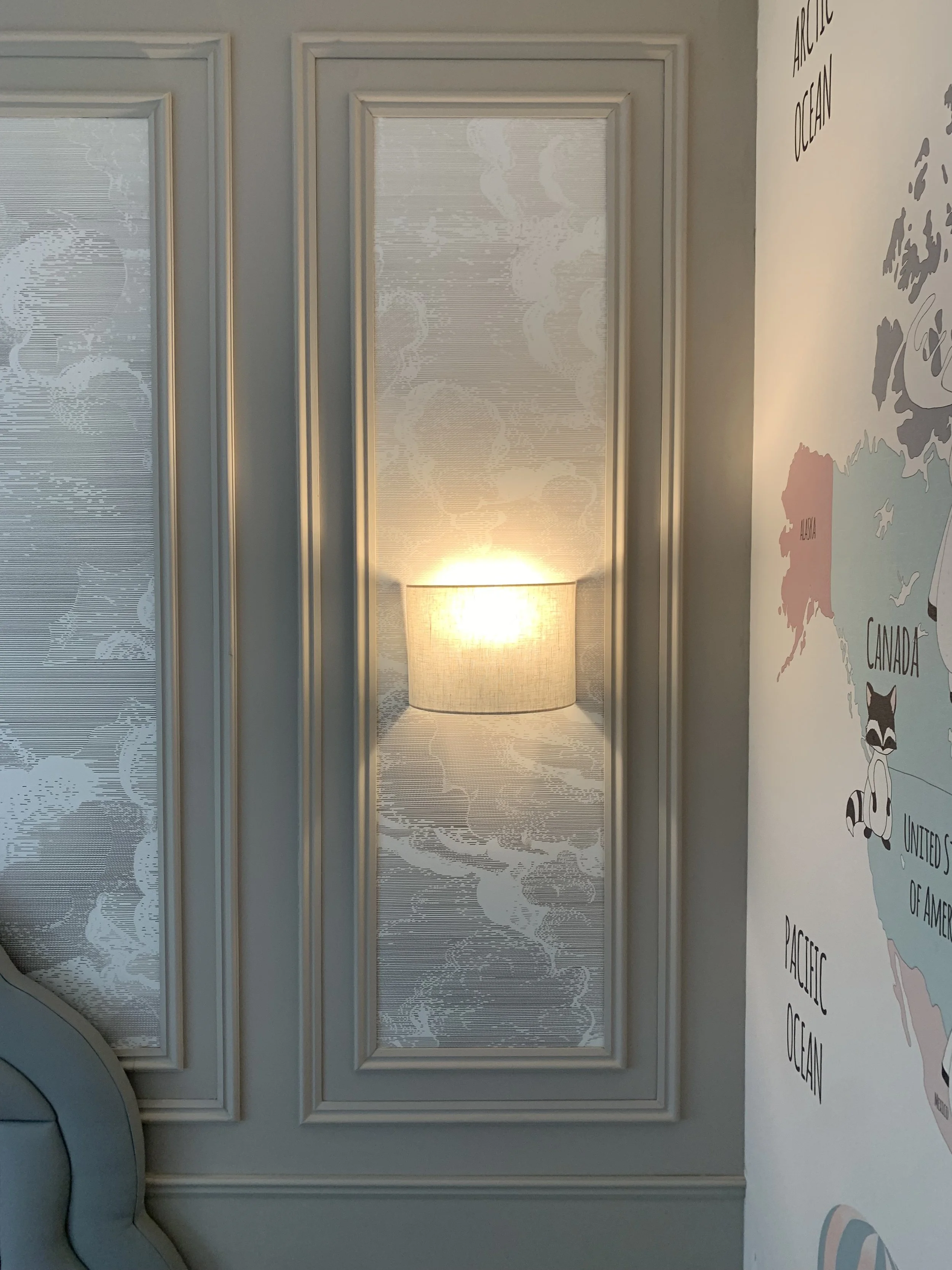 Interior wall with framed panel mirrors and a lampshade that reflects the room's lighting. Part of a wall map showing North America and adjacent oceans.