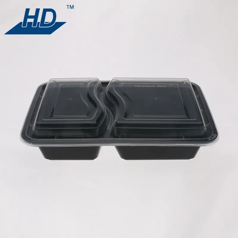 A dual-compartment black plastic food container with a clear lid, placed on a plain white surface. The logo 'HD' is visible in the top left corner.
