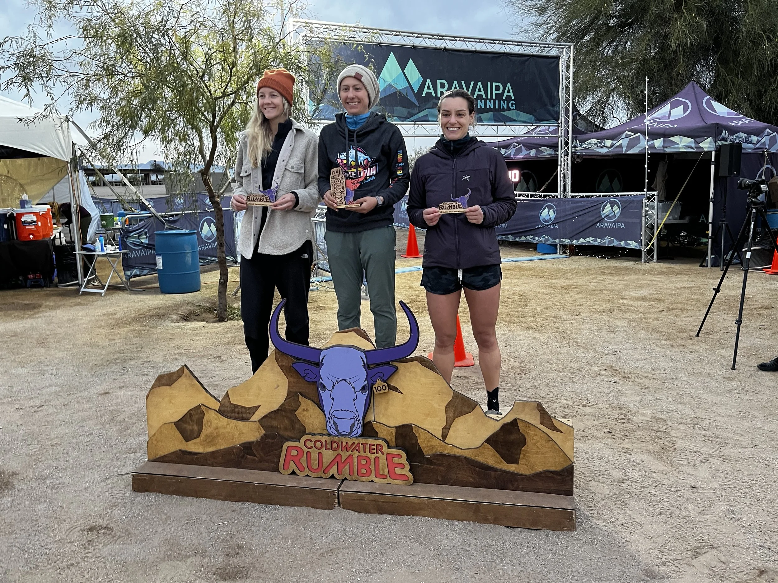 Three women standing on a podium after finishing a desert ultra running race.