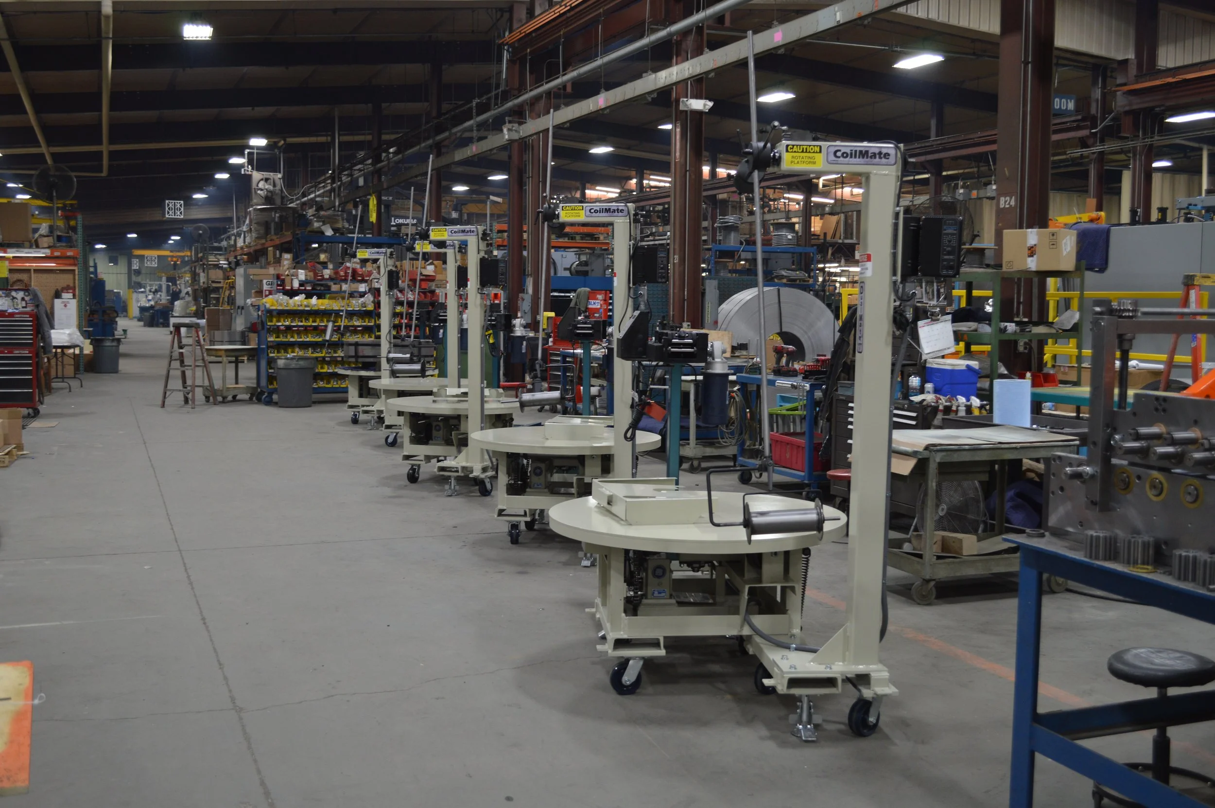Industrial manufacturing factory with automated machinery and workstations lined up in a large warehouse space.