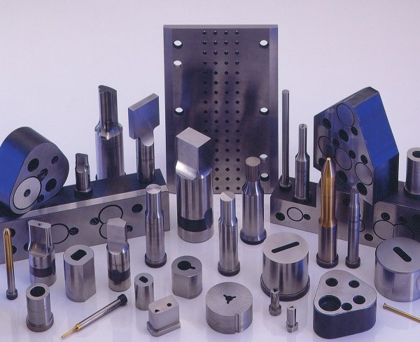 Various metal machine parts and tools arranged on a white surface.