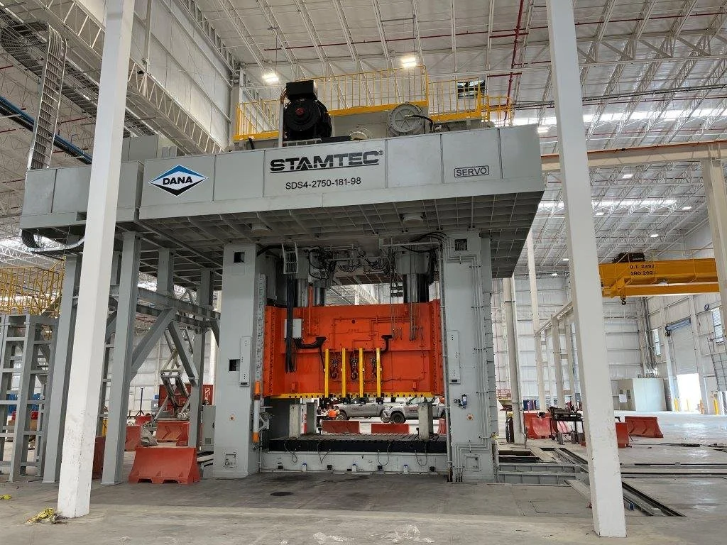 Large industrial machine inside a spacious warehouse, used for manufacturing or assembly, with the brand name 'STAMTEC' and 'DANA' on it.