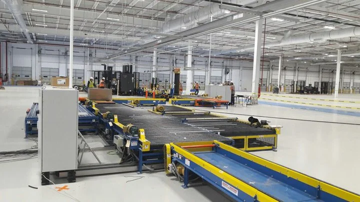 Industrial warehouse with automated conveyor system and workers in the background.
