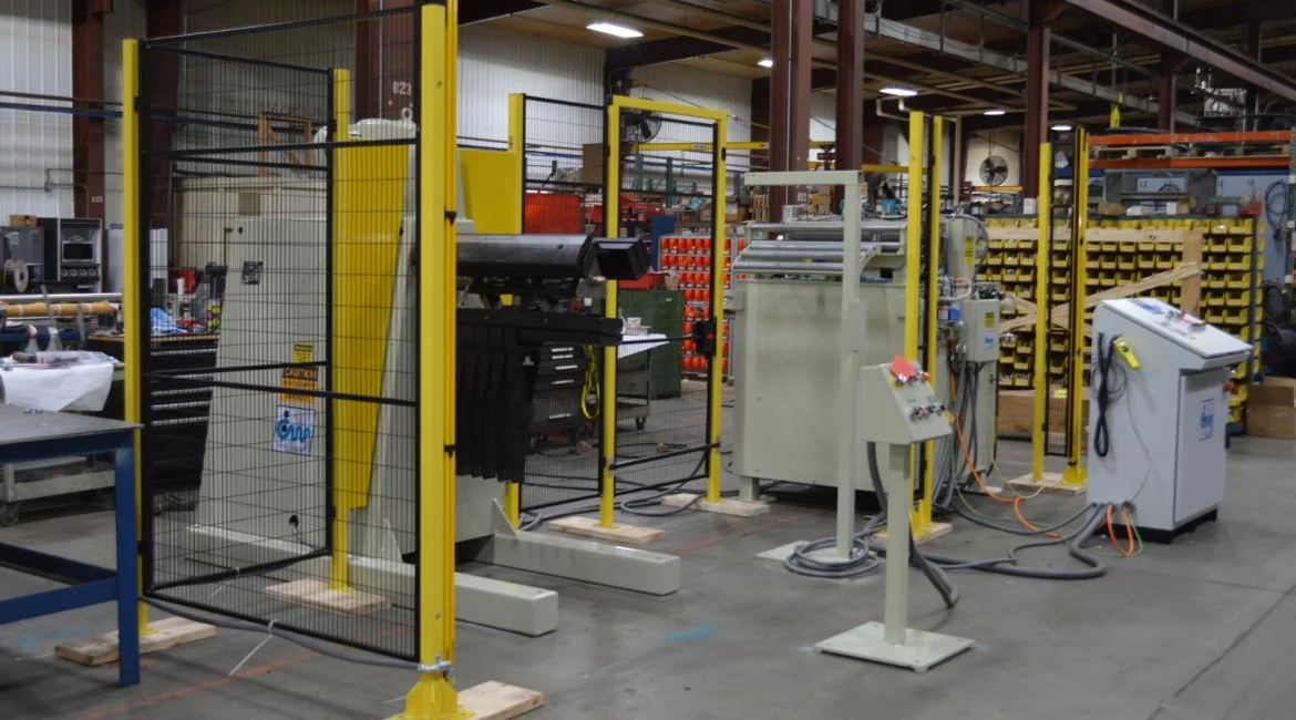 Industrial workshop with machinery, safety barriers, and storage racks.