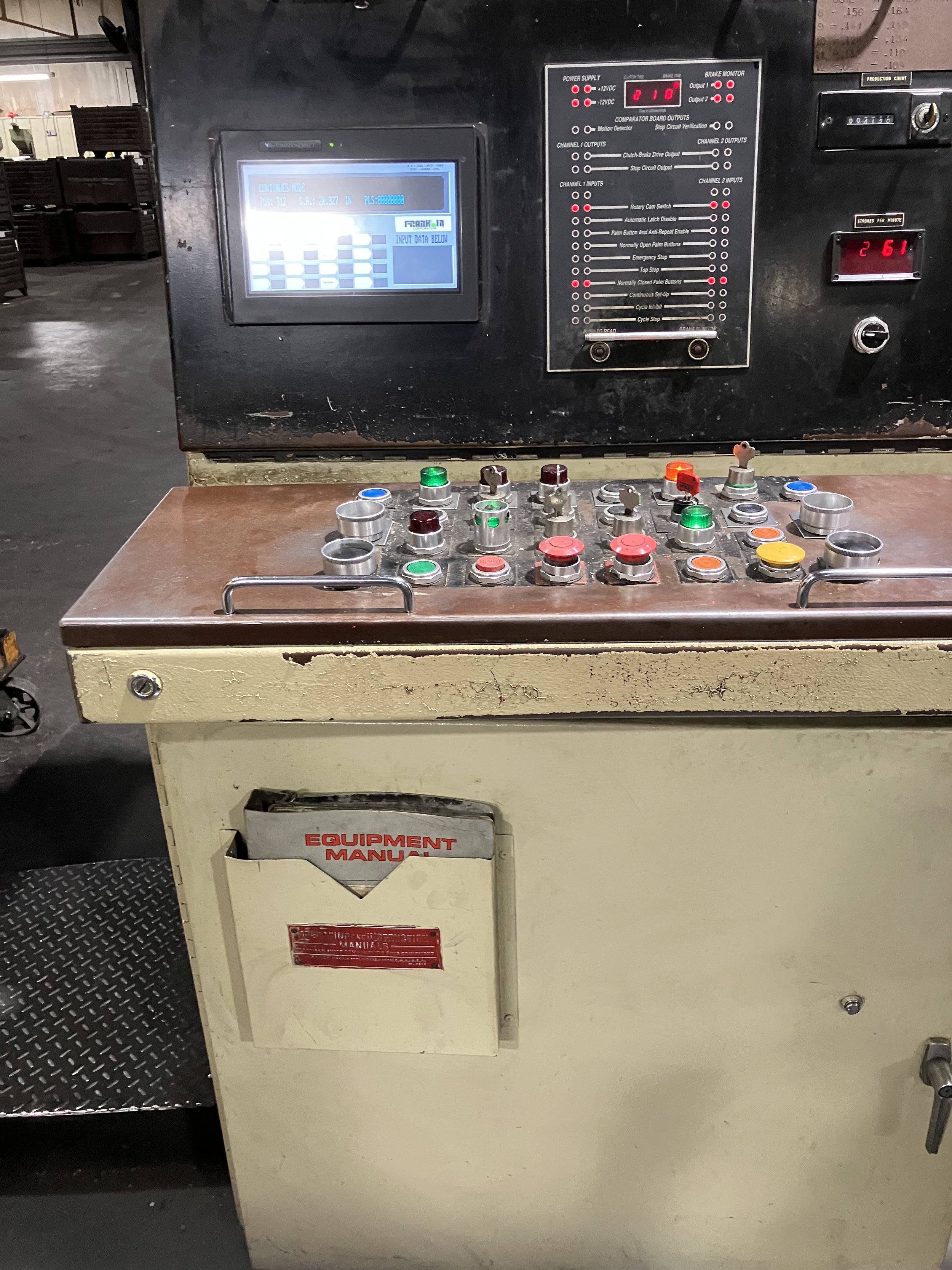 An industrial control panel with various buttons, LEDs, and a digital display, used to operate and monitor machinery in a factory or workshop.