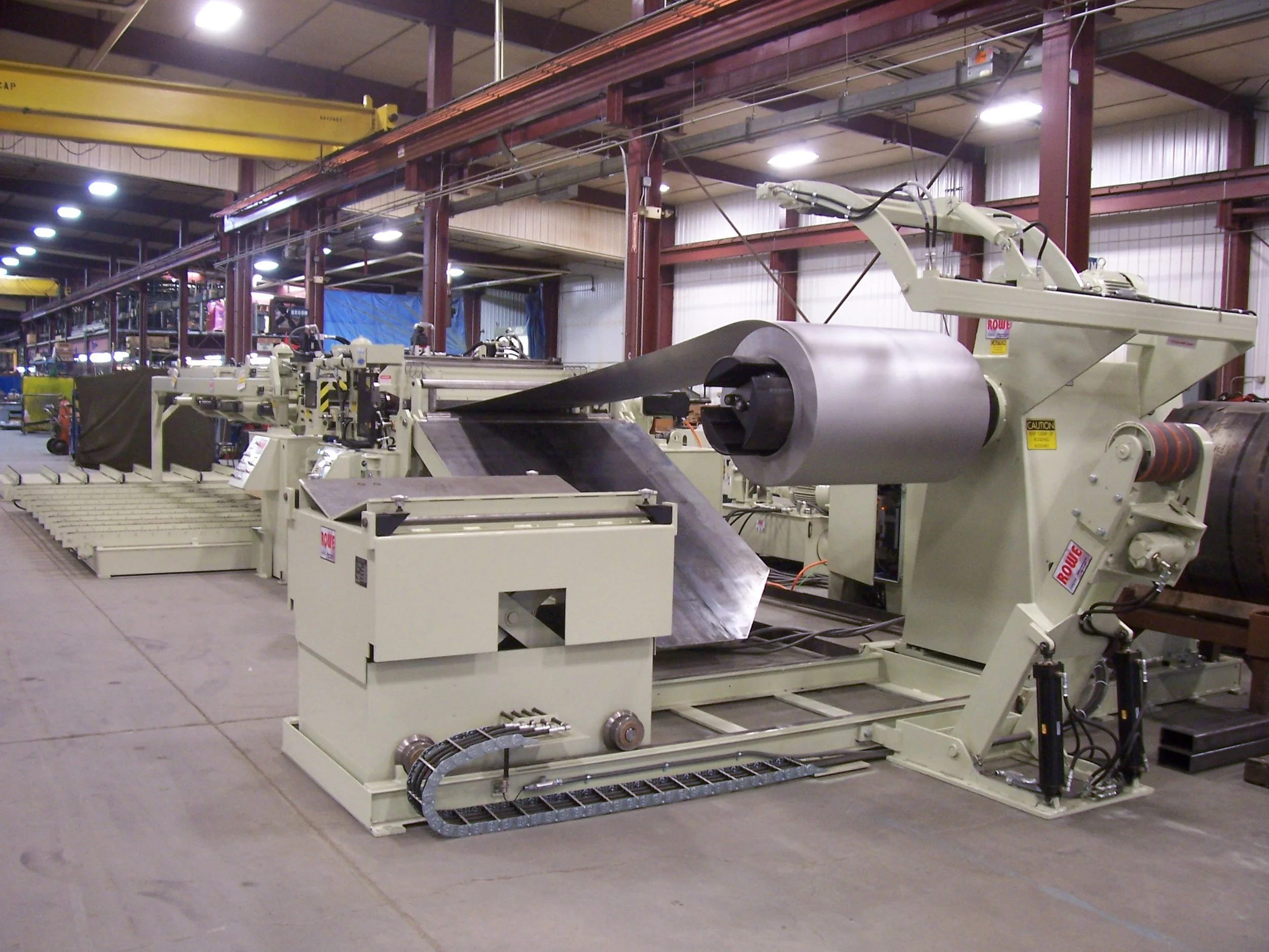 Industrial manufacturing equipment in a factory setting with mechanical arms and a conveyor system.