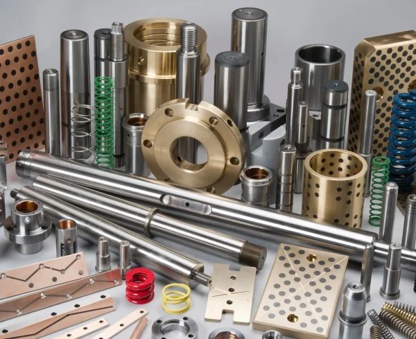 Various precision machine parts including cylindrical rods, gears, springs, and metal plates on a flat surface.